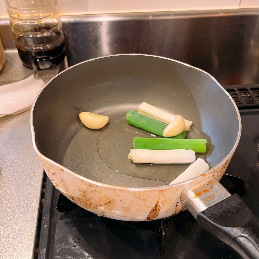 油、長ねぎ、にんにくが入った鍋の中に、たっぷりの鰹節を投入した様子。
