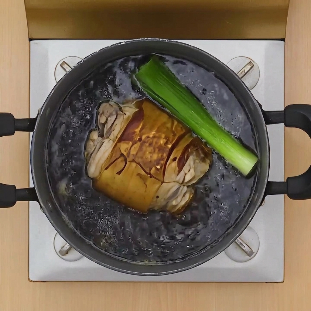 肉が浸かった煮汁の中に、ねぎや生姜を投入している様子。