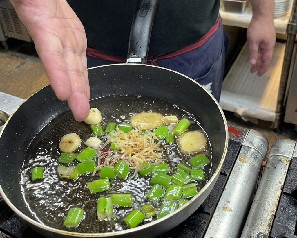 香味野菜を炒めている油に干しえびを投入している様子。
