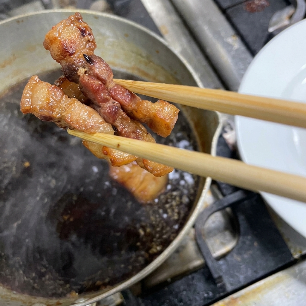 タレの中からよく煮込まれたチャーシューを取り出している様子。