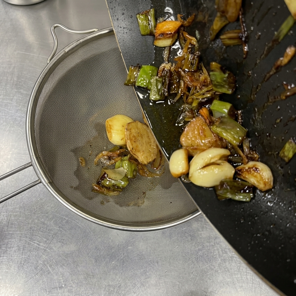 香味野菜を炒めた熱い油を濾している様子。