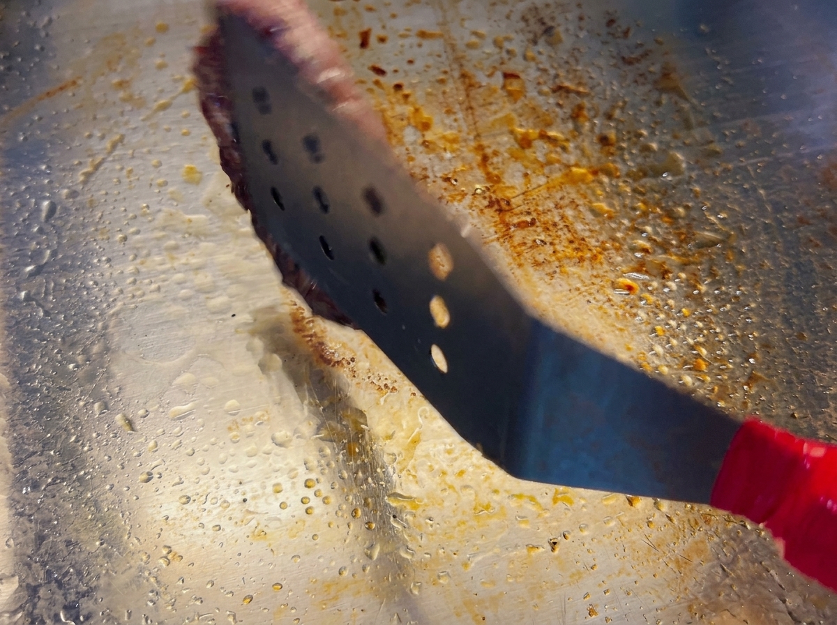 スパチュラでパティを裏返し、こんがりと焼けた表面が見えている様子。