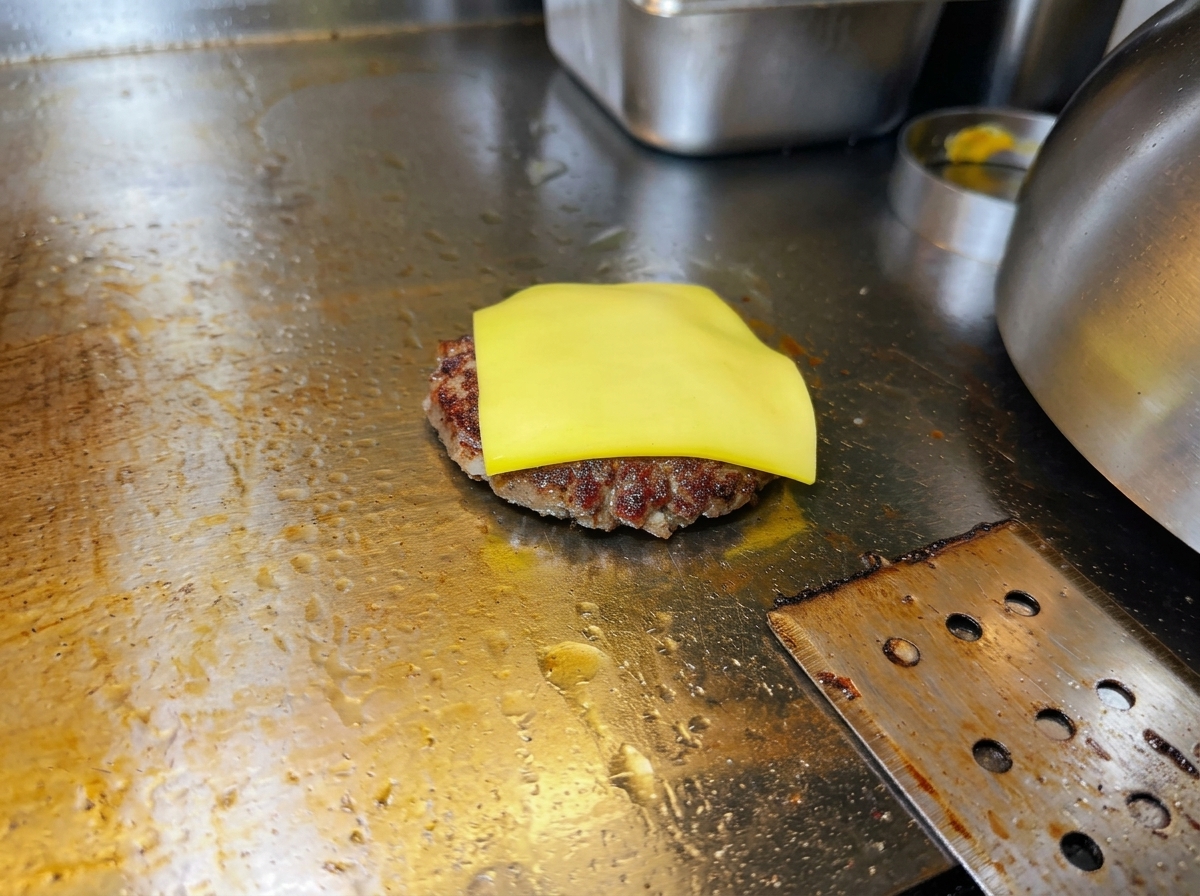 パティの上で黄色いチェダーチーズが溶け始めている様子。