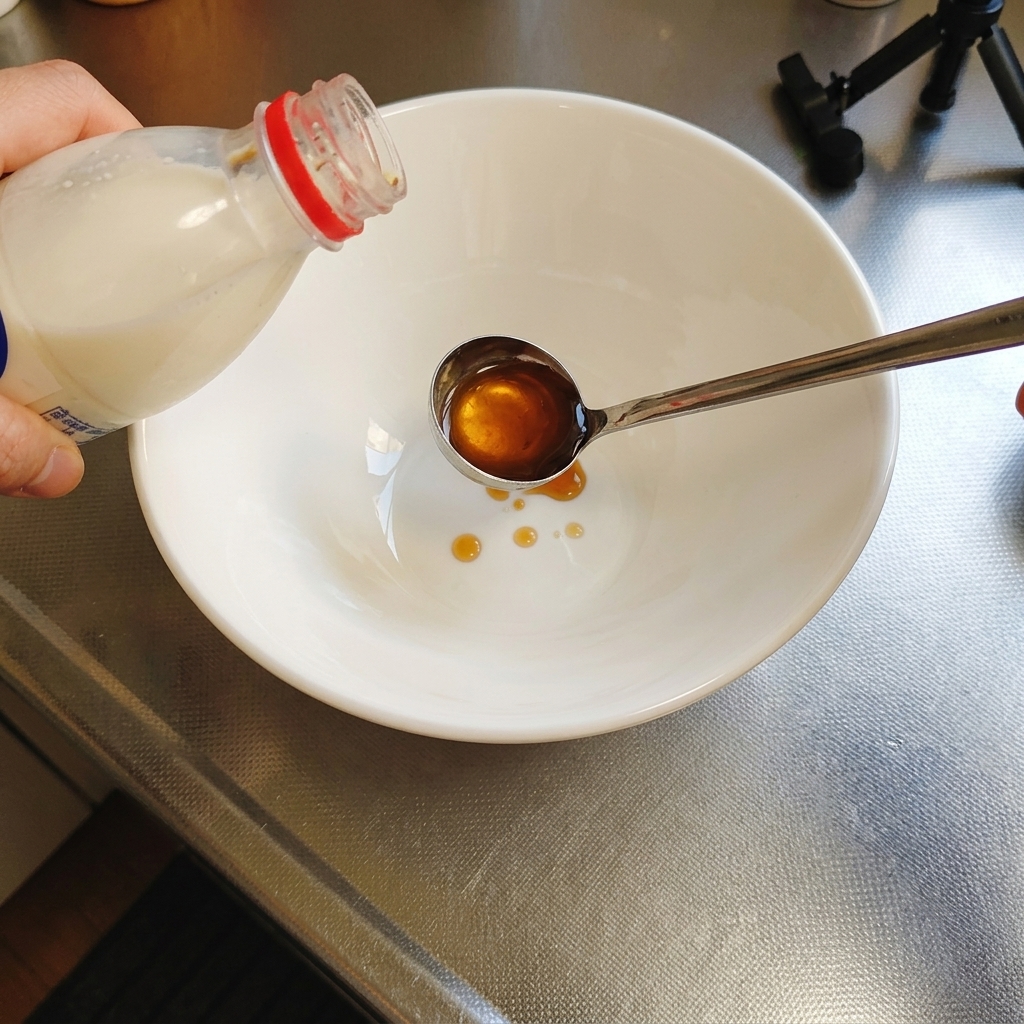 清潔な白いラーメン丼に、ベースとなる塩だれを注ぎ入れている様子。