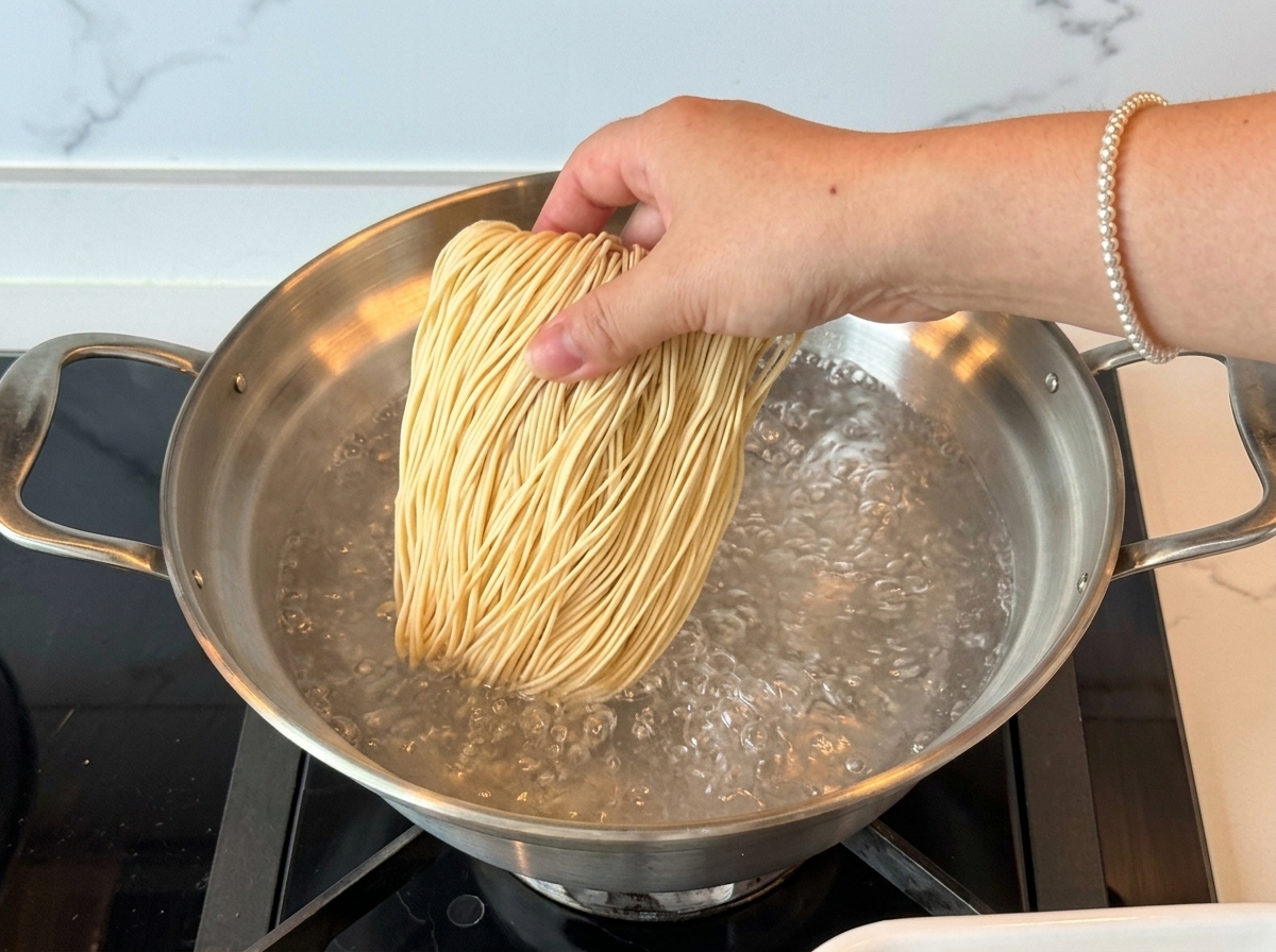 沸騰したお湯に、乾燥ラーメンの麺を入れている様子。