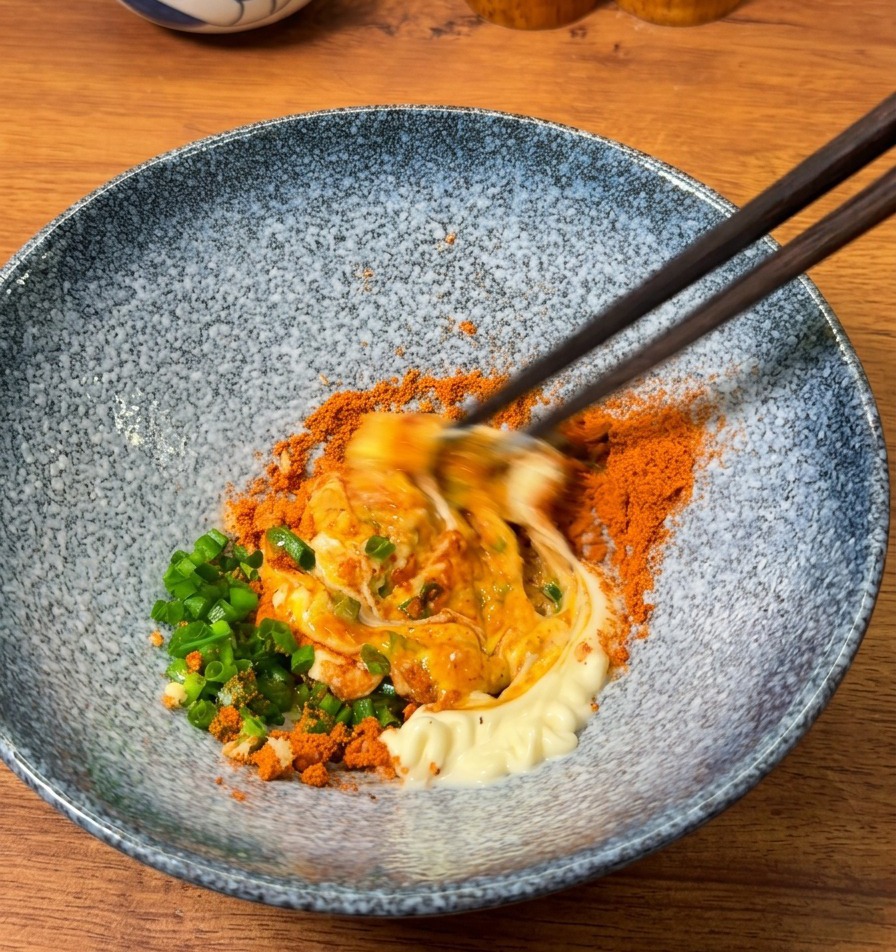 箸を使って卵黄、マヨネーズ、調味料を力強く混ぜ合わせ、厚みのあるペーストを作る様子。