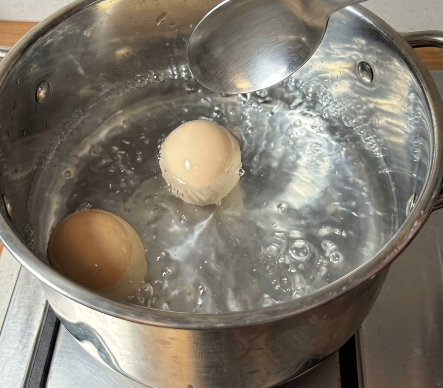 沸騰した鍋の中で、2個の卵が茹でられている様子。
