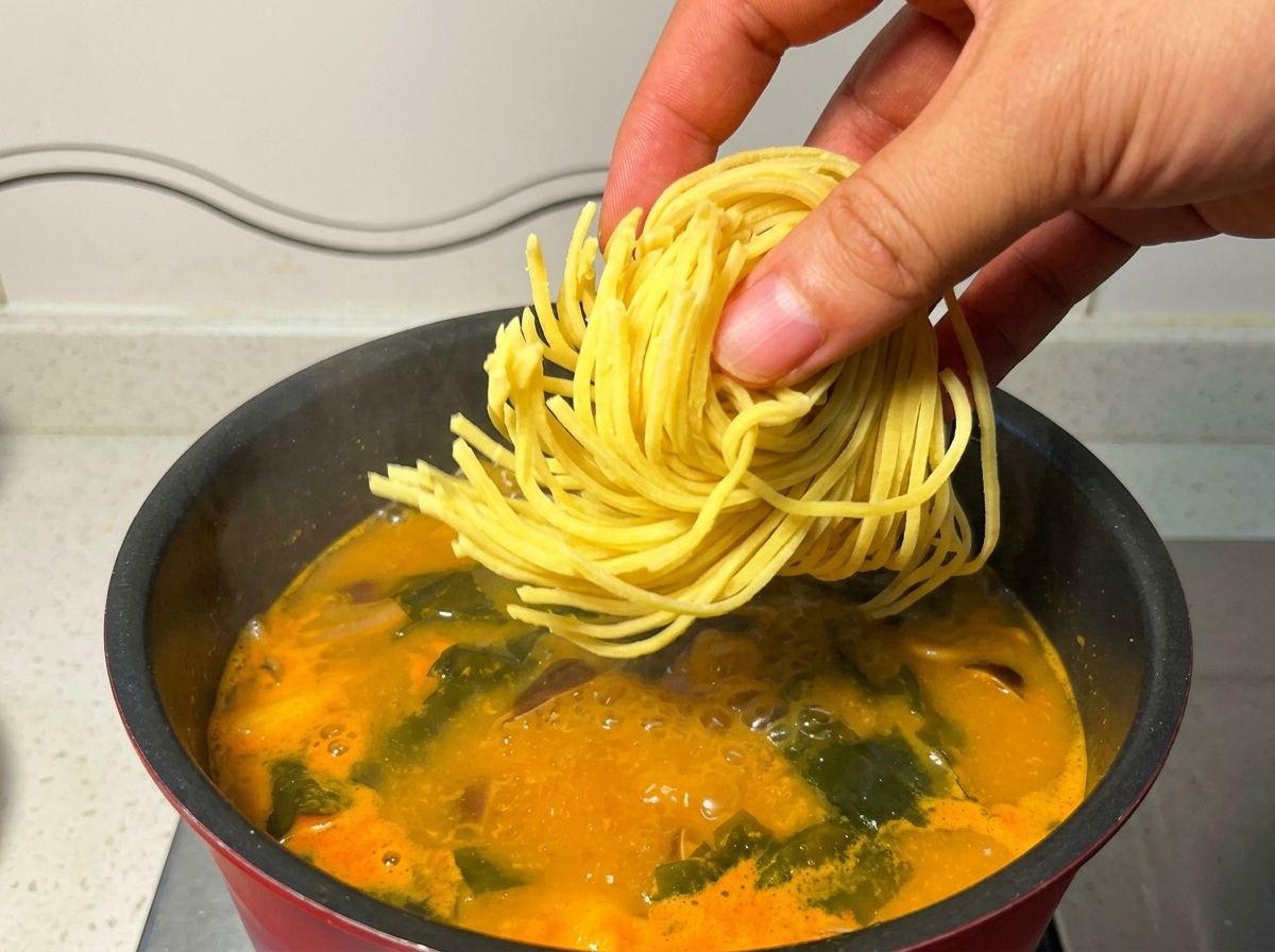 沸騰したスープの中に、生のラーメンの麺を投入している様子。