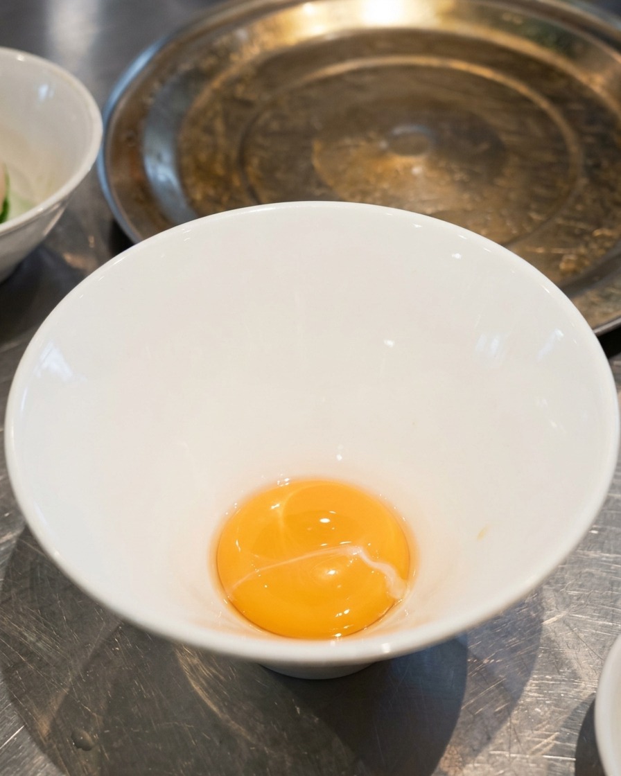 白い陶器のラーメン丼の底に、黄金色の塩ダレが入っている様子。