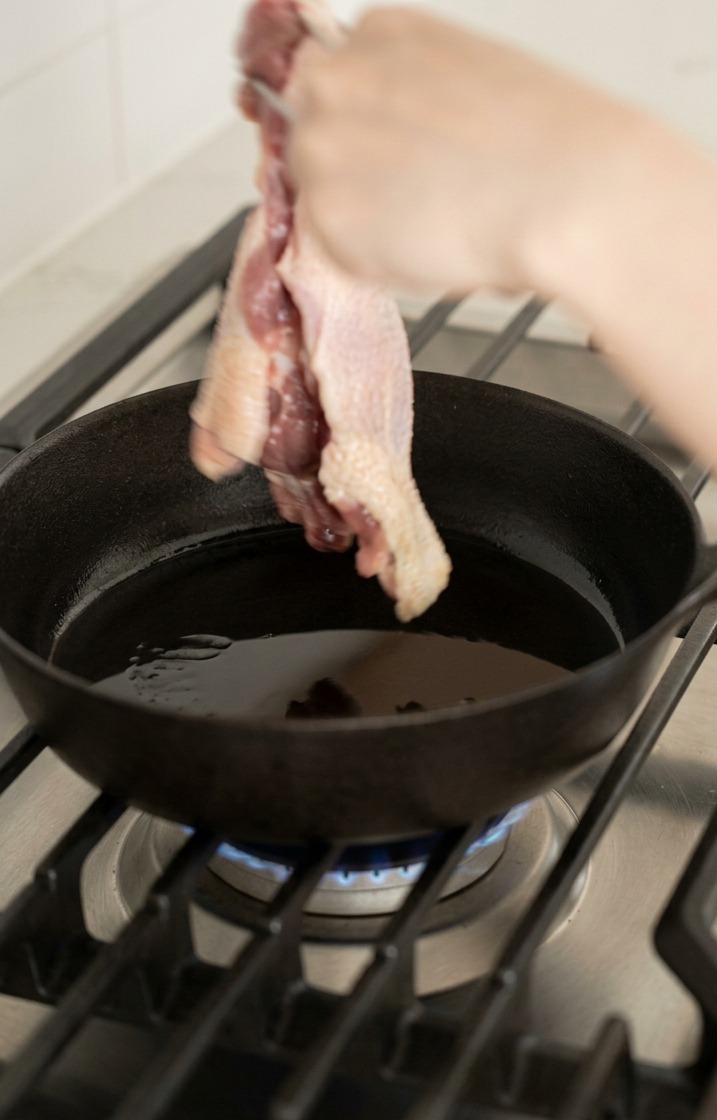 熱した鋳鉄製のスキレットに、鴨もも肉を皮目から入れる様子。