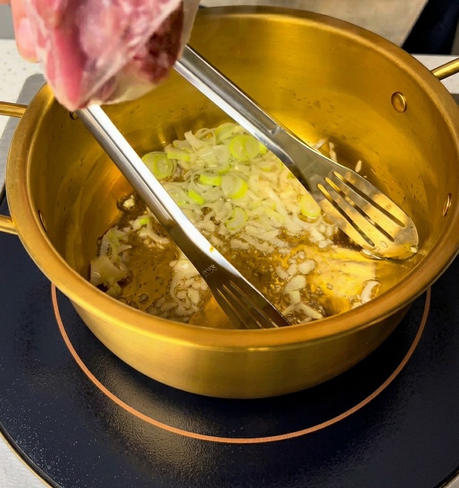 鍋の底で刻んだ長ねぎとにんにくを炒めている様子。
