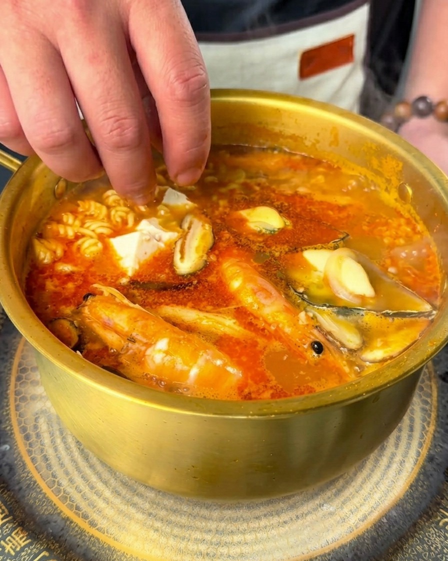 豆腐と唐辛子の輪切りを熱々のラーメンに加えている手元。