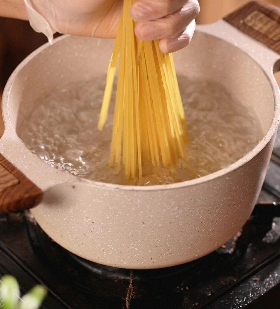 沸騰したお湯に乾燥スパゲッティを入れる様子