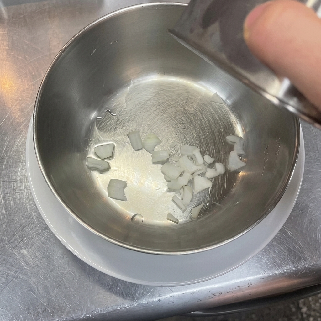 きれいなステンレス製のボウルの底に、細かくみじん切りにした白玉ねぎが入っている様子。