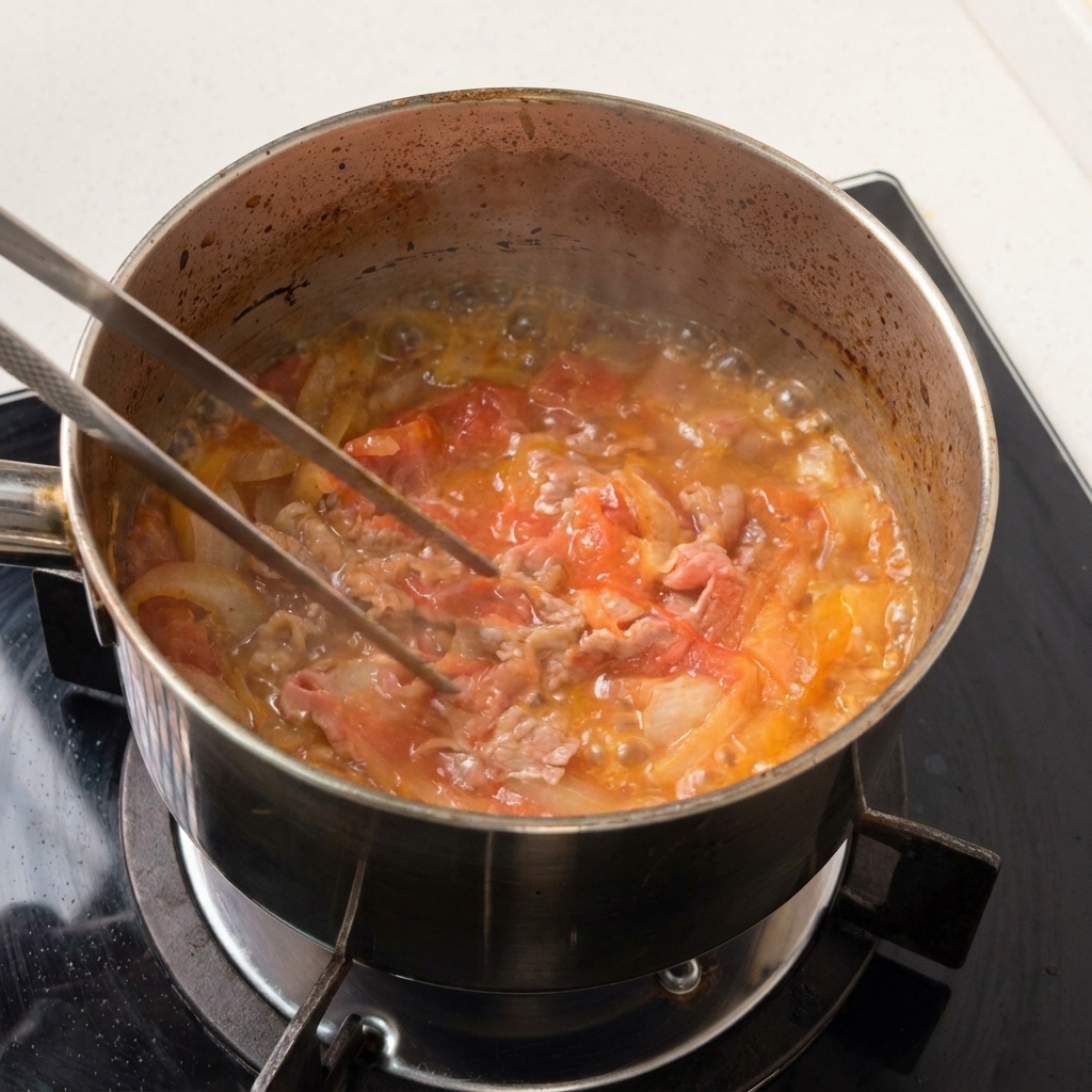 少なめの濃い煮汁の中で、薄切りの牛肉と玉ねぎが優しくふつふつと煮えている様子。
