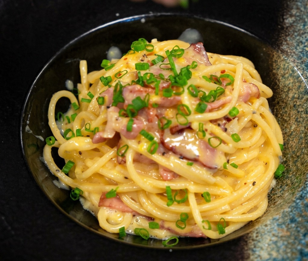 お皿に盛り付けたパスタに刻みねぎを散らす様子