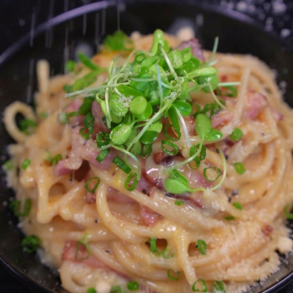 完成したパスタの上にさらにチーズを削る様子