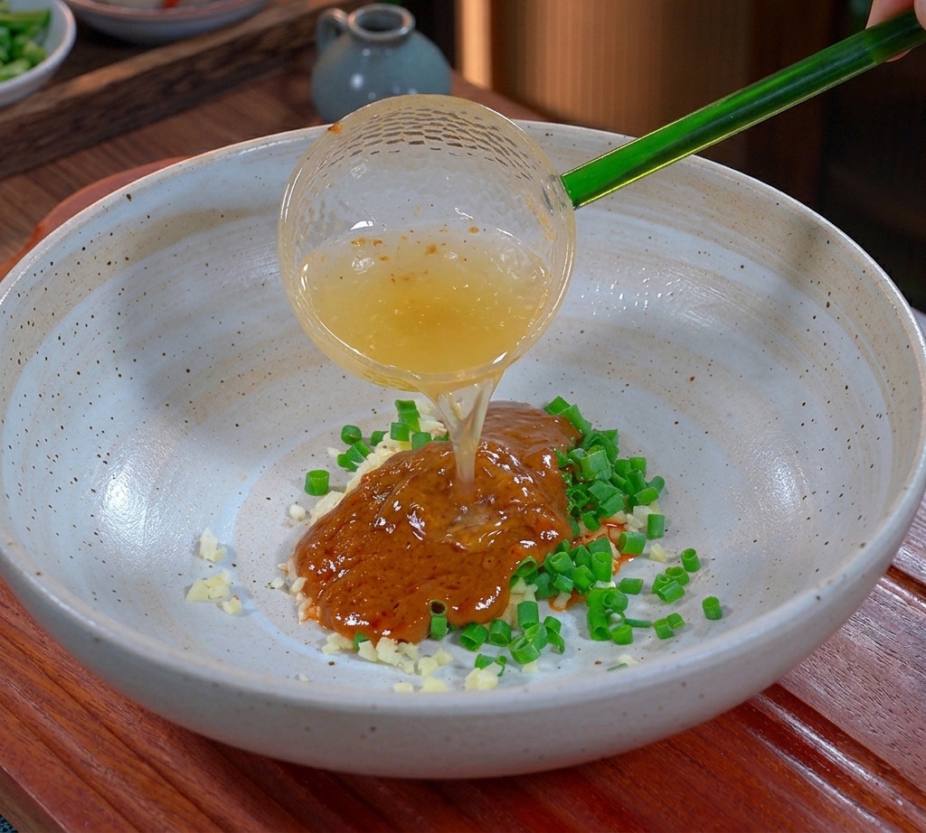 半透明の緑のお玉から、調味料の入った器へと注がれる黄金色の液体状の豚の脂