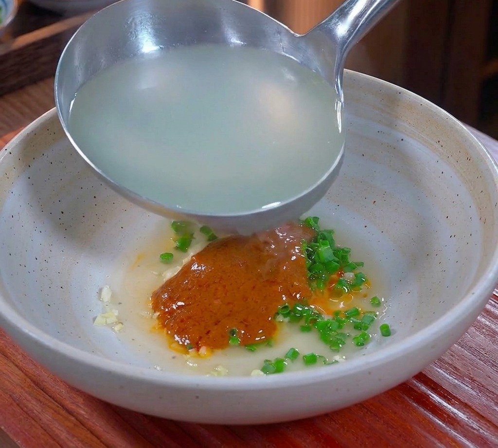 辛い調味料と豚の脂が入った器に、お玉で注がれる白濁した熱々の麺の茹で汁