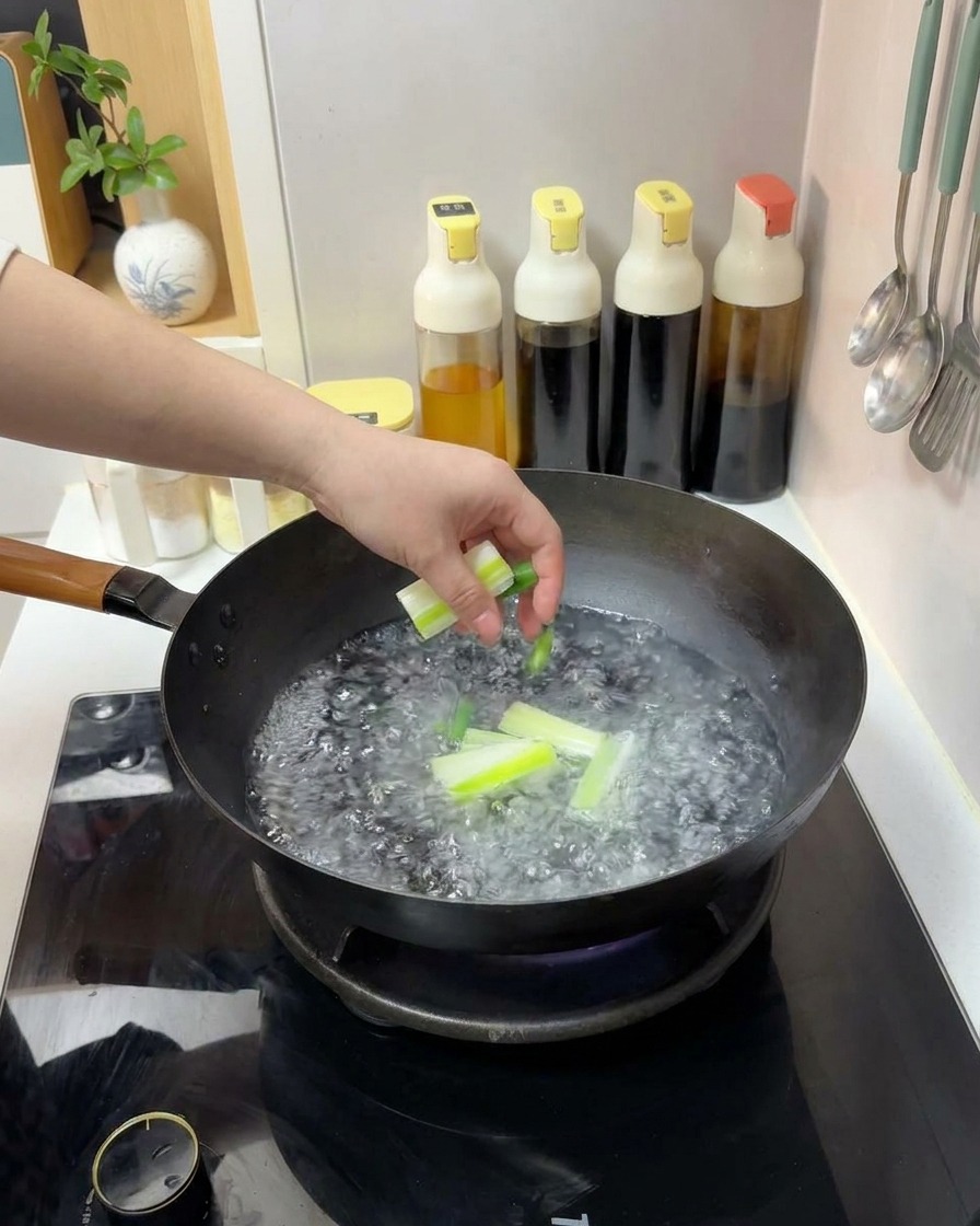 沸騰した中華鍋に、カットした長ねぎを投入している手。