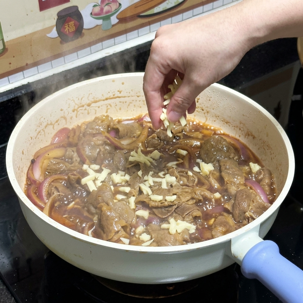 フライパンの中の照り焼き牛肉の上に、ピザ用モッツァレラチーズをたっぷりと振りかけている手元。