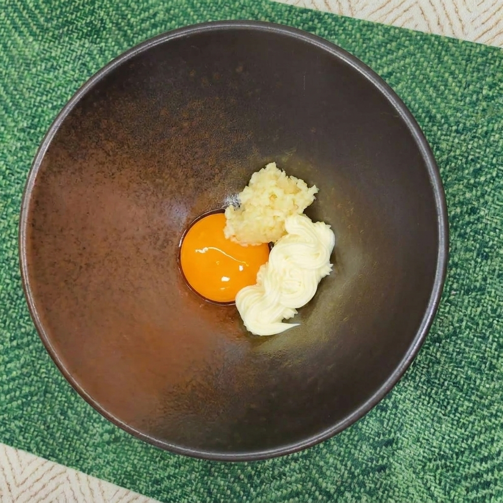 卵黄、マヨネーズ、にんにくが入ったボウルに、ラーメンの粉末スープが振りかけられた状態。
