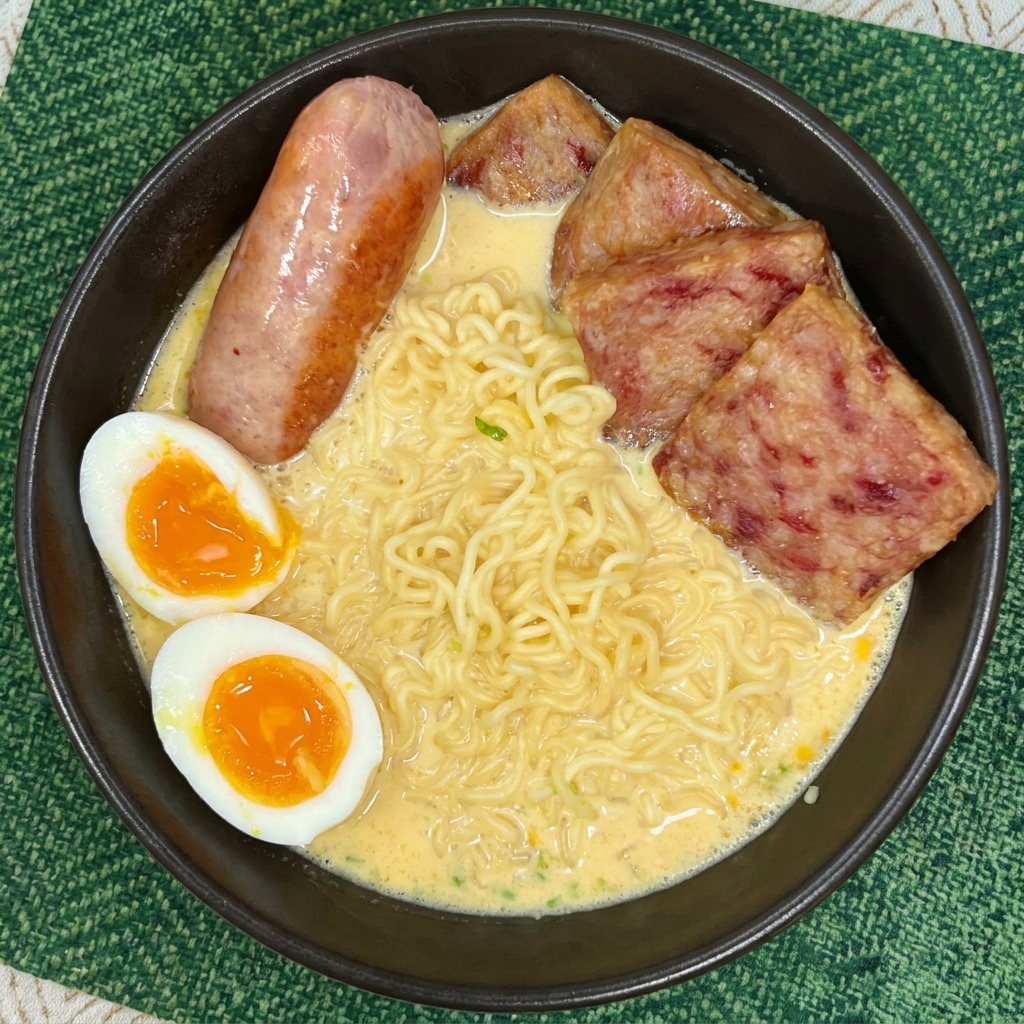 スパム、ソーセージ、そして黄身がとろりとした半熟卵が盛り付けられたラーメン鉢。