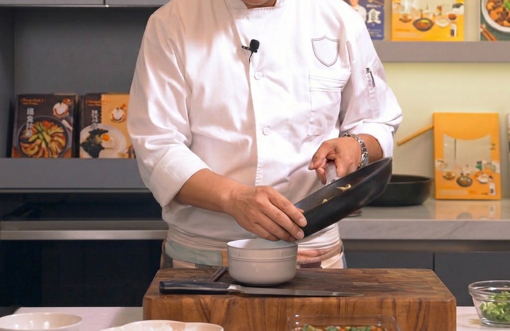 フライパンから温かい白米が盛られた丼に、とろとろの卵と鶏肉の具材を滑らせるように乗せている様子
