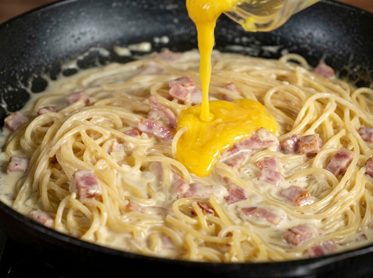 火を止めたパスタに卵黄ペーストを加える様子。