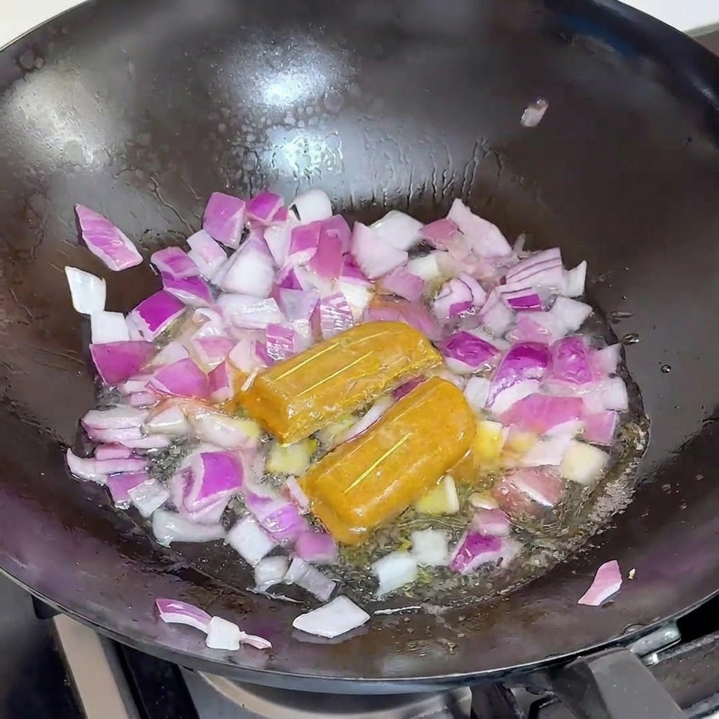紫玉ねぎとカレールーの入った鍋に水を注いでいる様子。