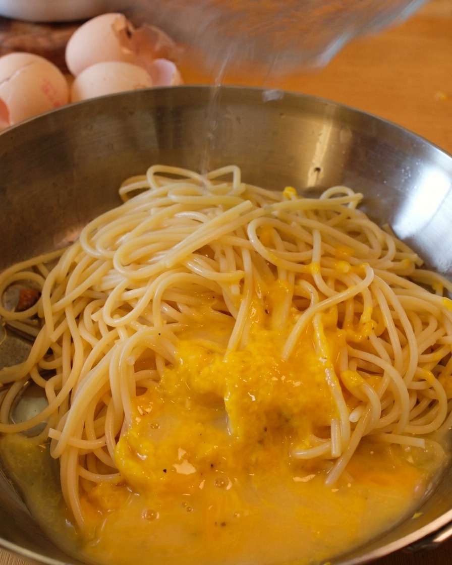 ソースを和えているパスタに、さらに少量の茹で汁を加えて濃度を調整している様子。
