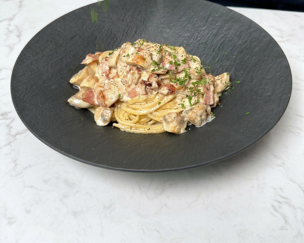 仕上げに刻んだパセリを振りかけ、パスタを完成させる様子