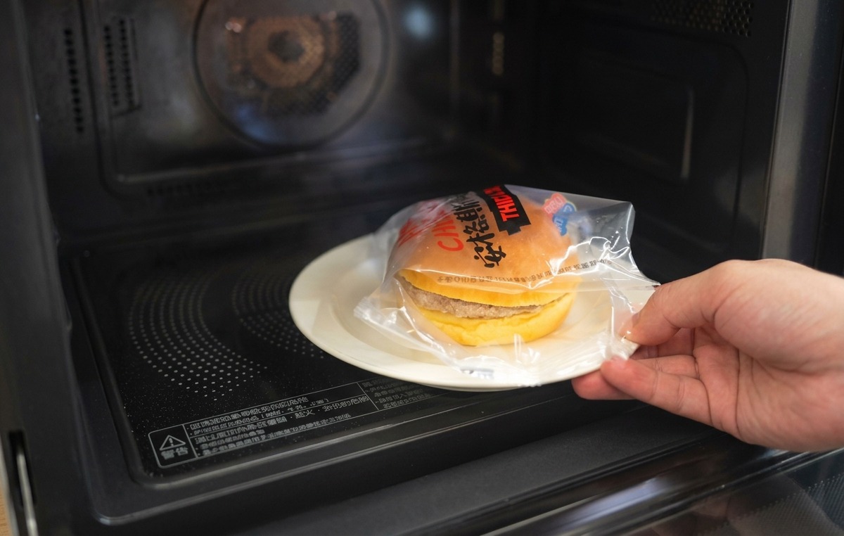 玉ねぎと溶けたチーズがのったバーガーに、こんがり焼けた上のバンズをのせている様子。
