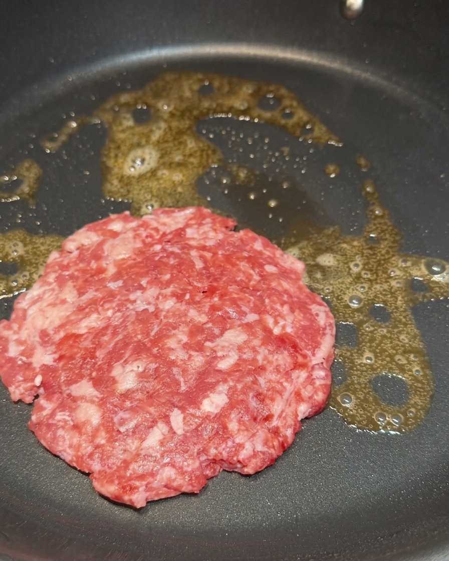 バターを溶かしたフライパンで、生のビーフパティを焼いている様子。
