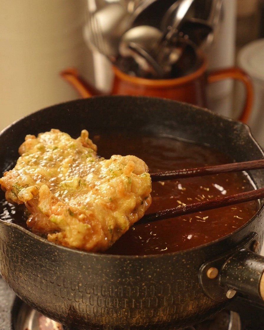 黄金色に揚がったクリスピーなチキンを箸で持ち上げている様子
