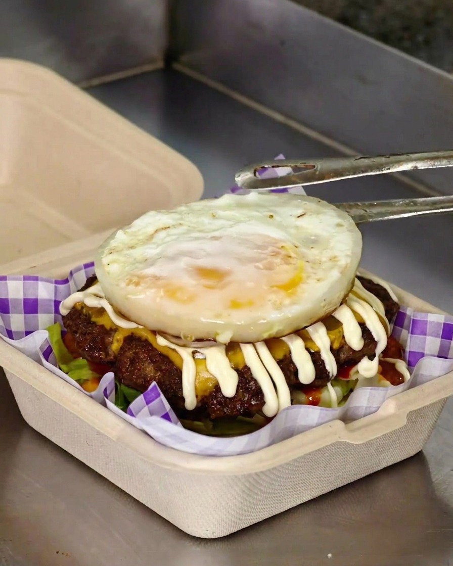 バーガーの仕上げに目玉焼きをのせている様子。
