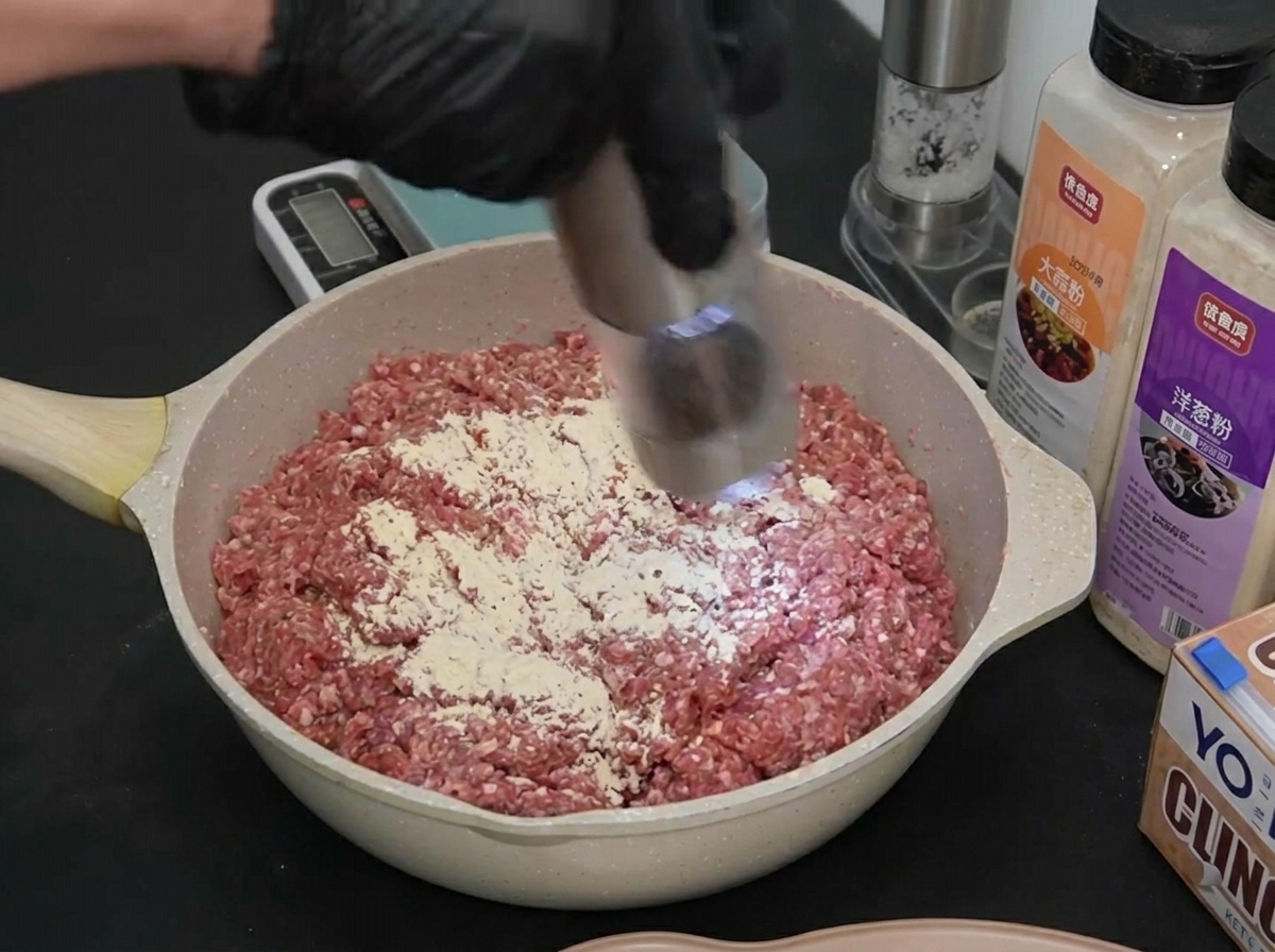 電動ミルを使って、味付けされた挽肉に黒胡椒を挽き入れている様子。