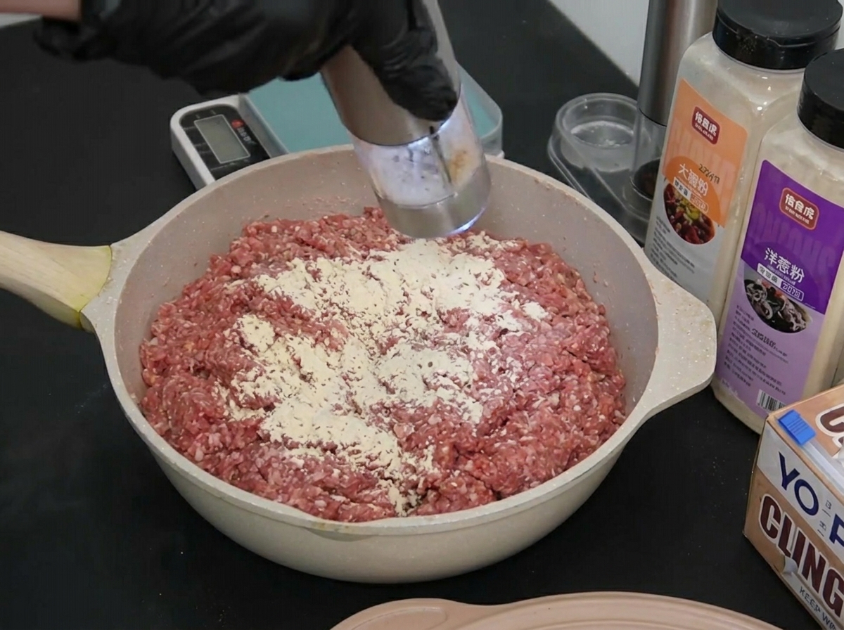 少量の海塩を挽肉の表面に軽く挽き入れている様子。
