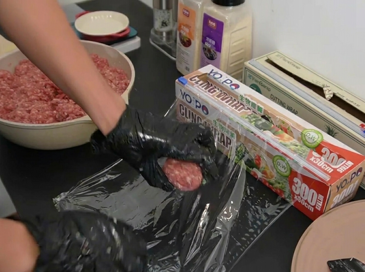 きれいに丸められた肉のボールを、広げたラップの上に置いている様子。