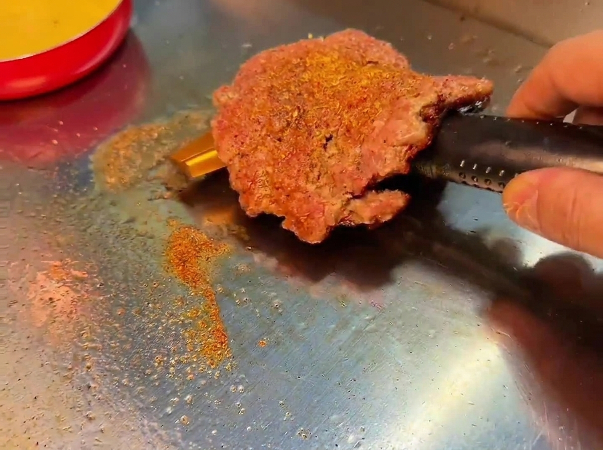 こんがりと焼き色がついたパティを裏返す様子