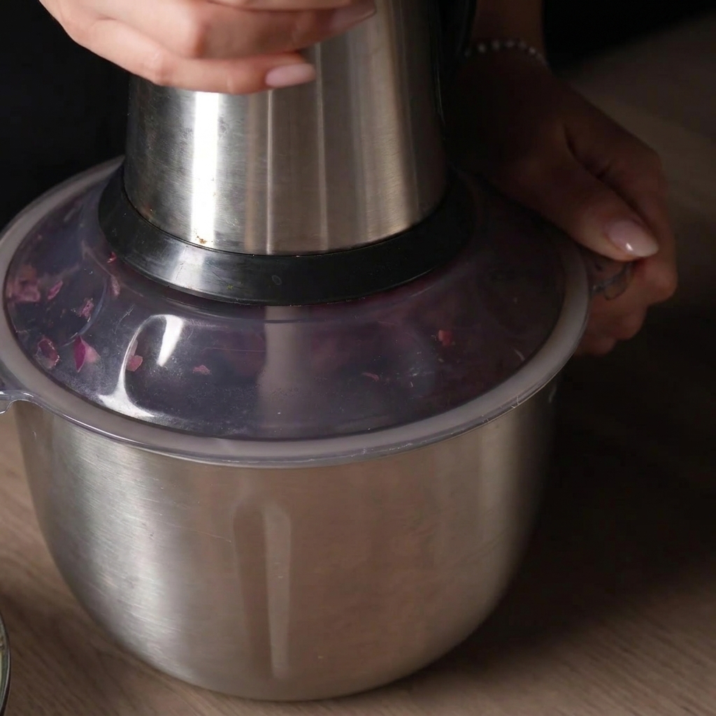 フードプロセッサーの蓋を押し、中の生肉をパルス状に粉砕している手。