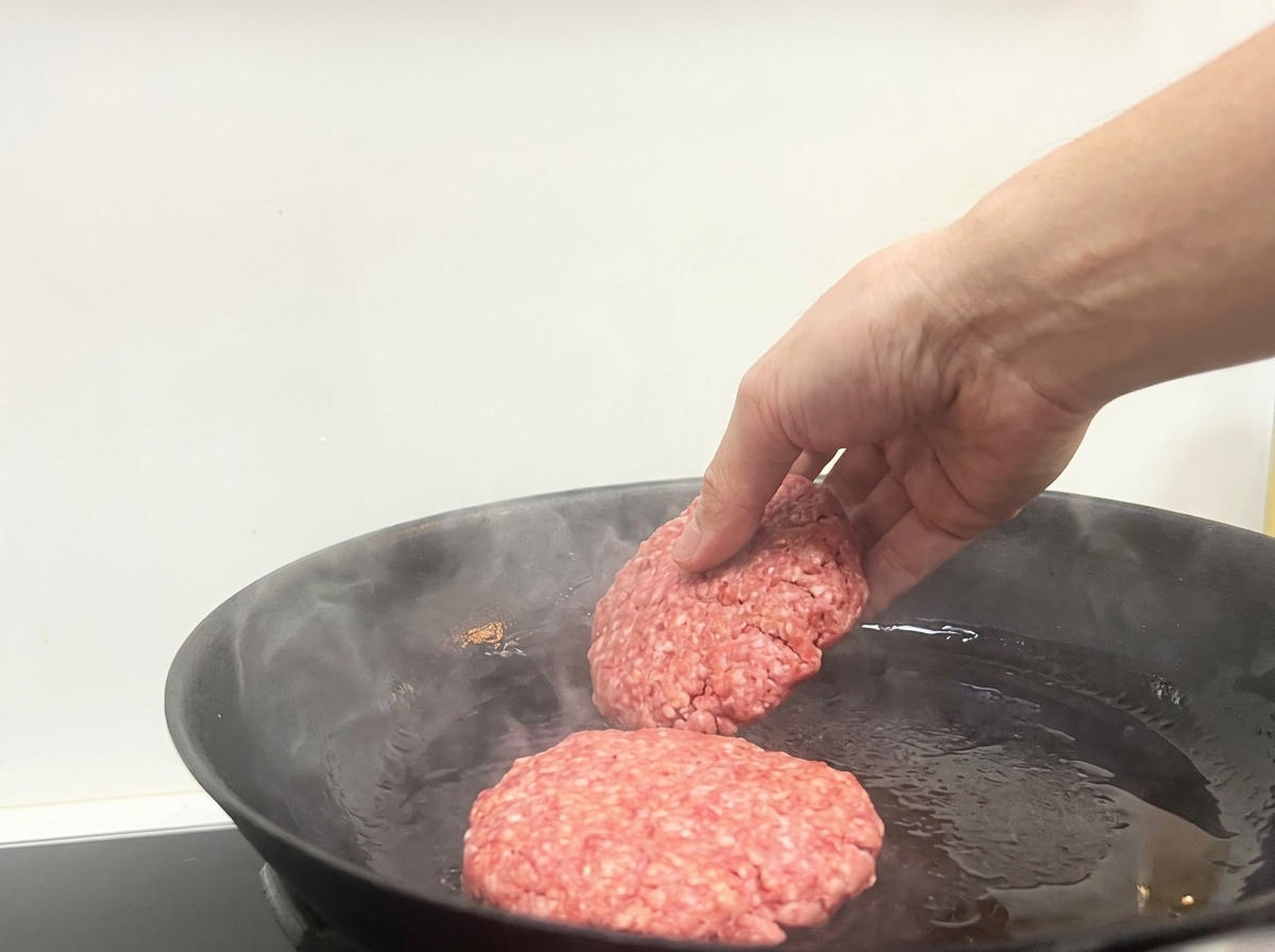 熱いフライパンに生のパティを並べる様子