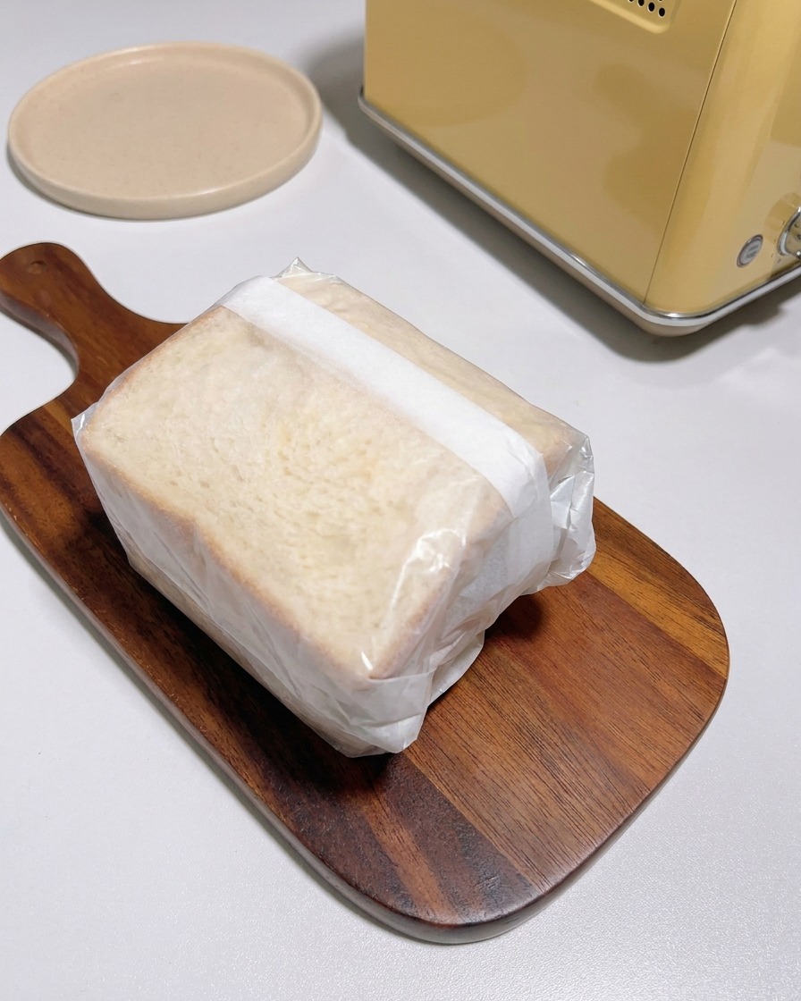 完成したサンドイッチをクッキングシートできっちりと包み、ボードに置いている様子。
