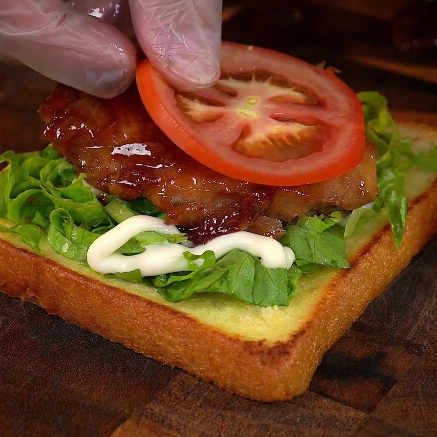 チキンの上にスライスしたトマトをのせている様子