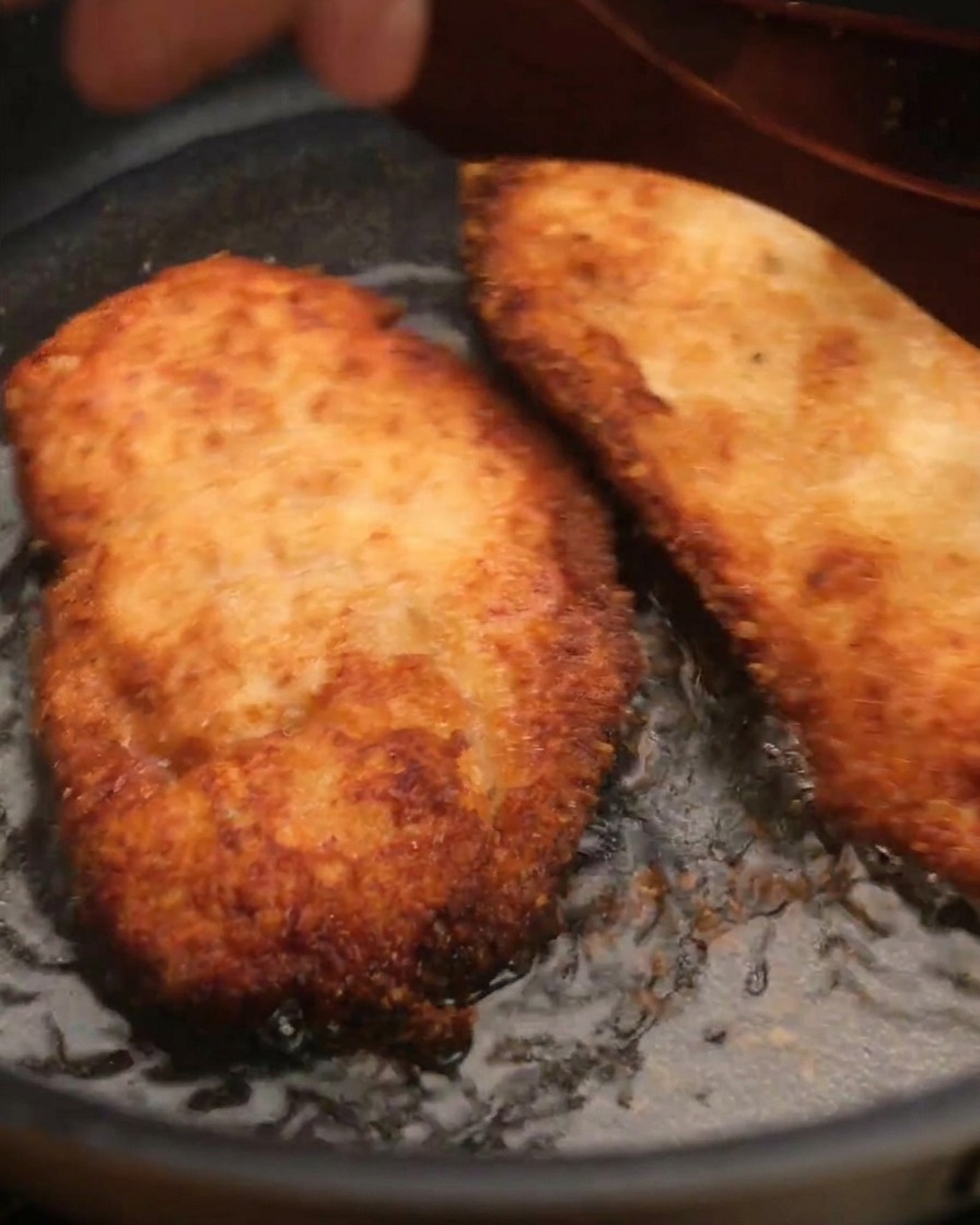 揚がったチキンを木製のヘラで油から引き上げている様子。