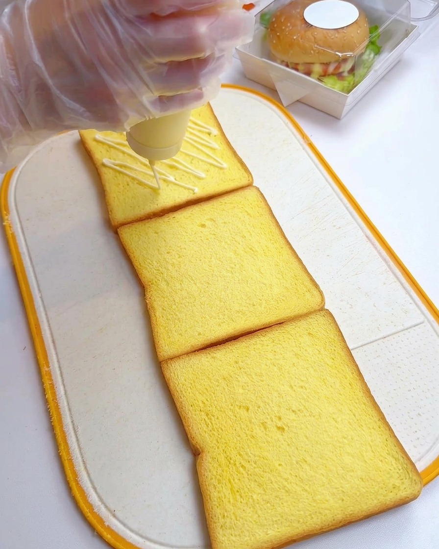 3枚の食パンの上にマヨネーズをジグザグに絞り出している様子。