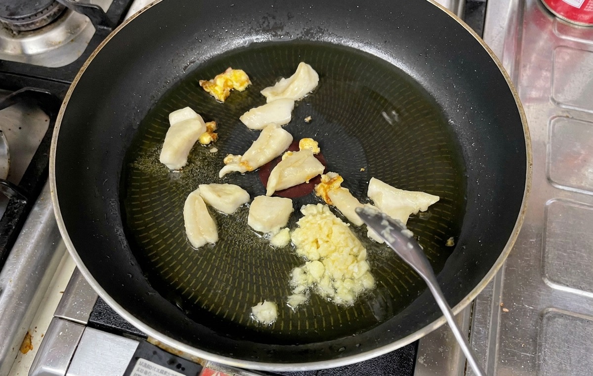 熱した油の中で、刻んだにんにくが黄金色に色づくまで炒められている様子。