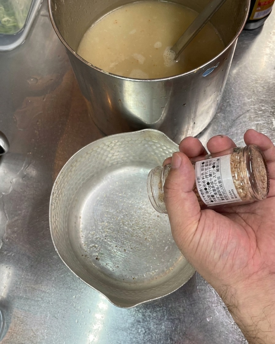 空の丼に、塩と魚醤を少しずつ入れている様子。