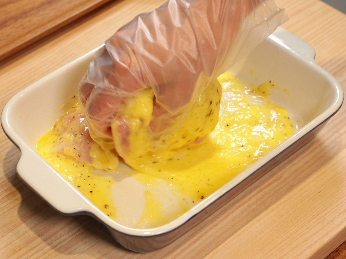 手袋をして鶏肉にマリネ液を揉み込んでいる様子
