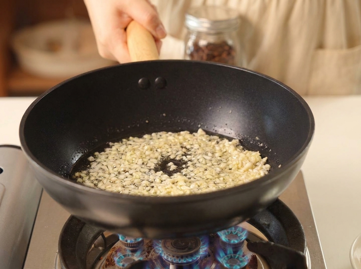 黒いフライパンで、熱い油に包まれながら泡立っているみじん切りのにんにく
